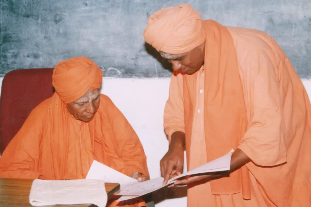 Two Swamijis reviewing a document together