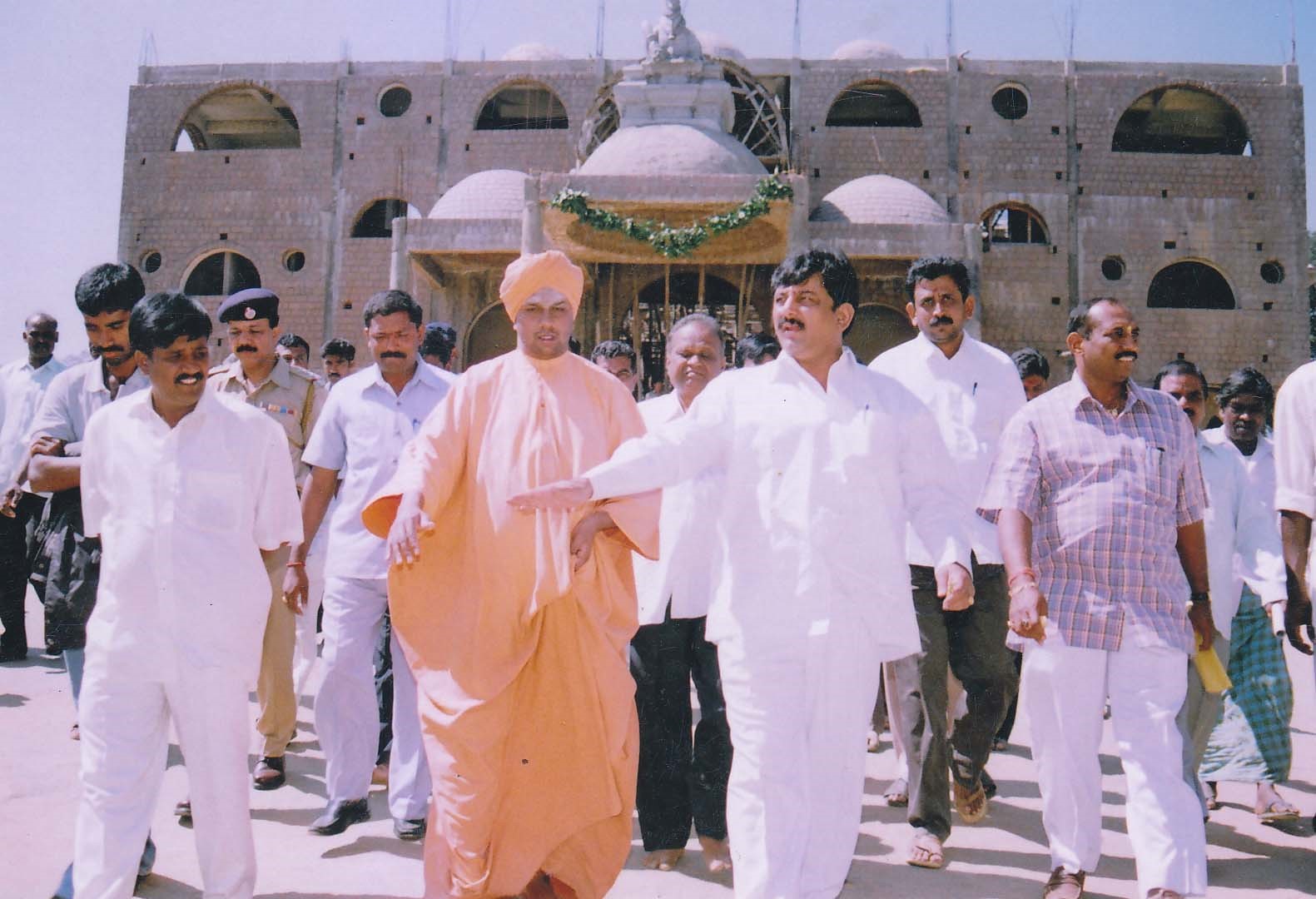 A Swamiji walking with public representatives in front of the temple complex