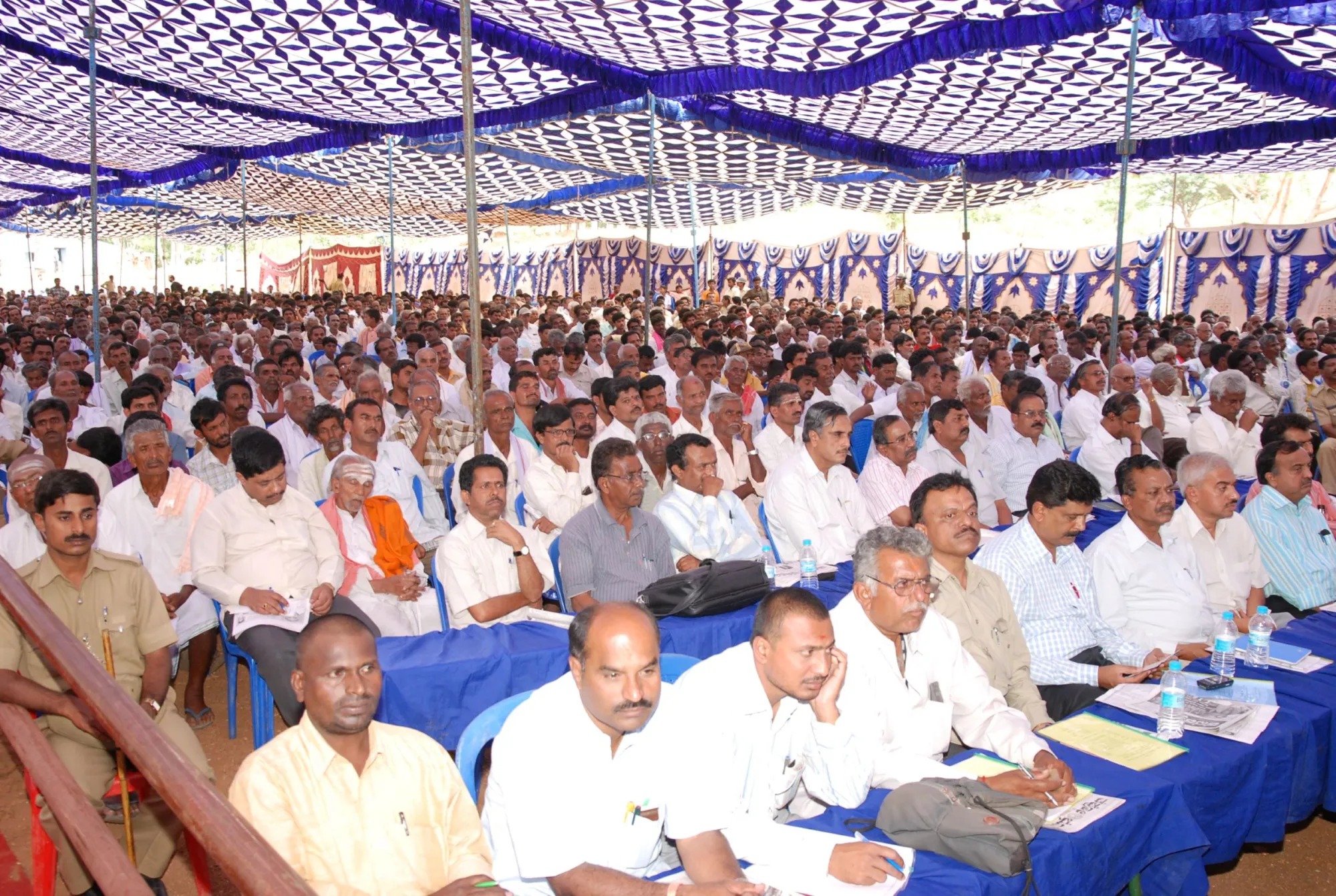 Large community gathering under a temporary canopy
