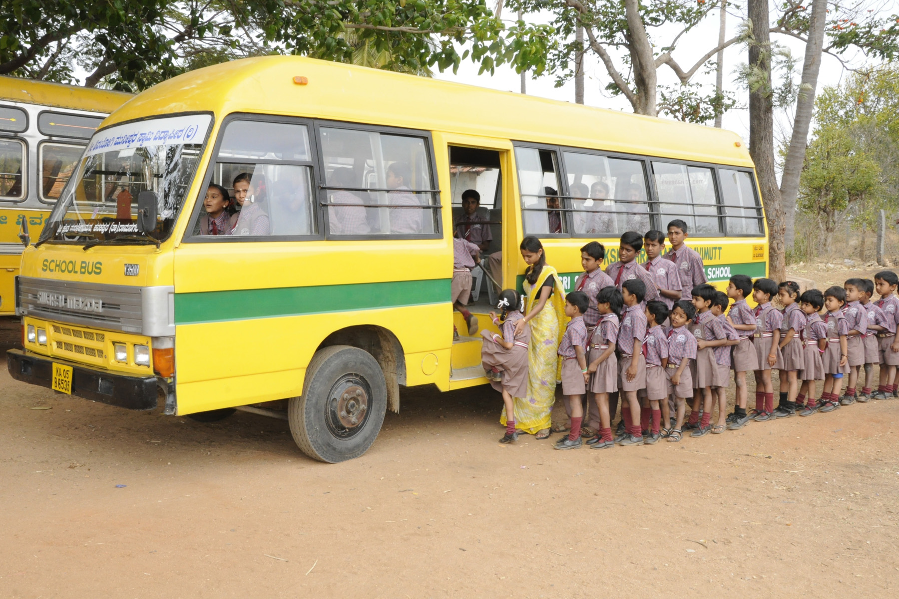 Vidya Peetha students boarding a school bus with their teacher